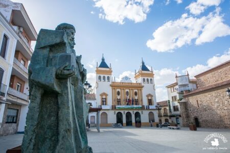 Escultura de San Juan de Ávila y San Juan Bautista de la Concepción con el ayuntamiento de Almodóvar del Campo de fondo